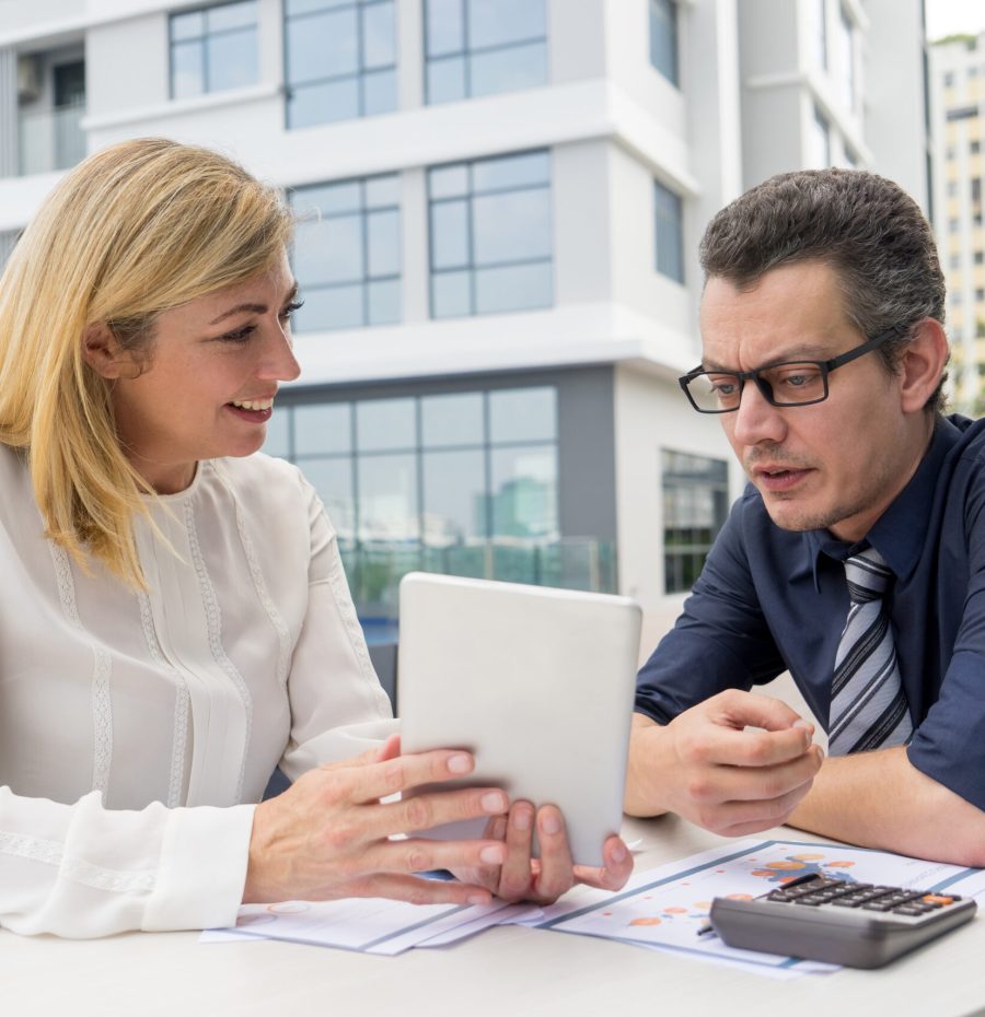 smiling-woman-showing-male-colleague-tablet-screen-cafe-outdoors-min